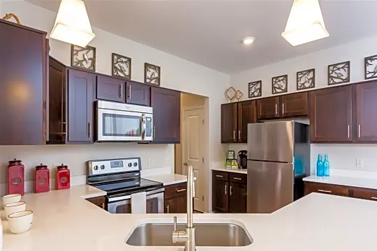 kitchen featuring electric range oven, stainless steel appliances, pendant lighting, dark brown cabinets, and light stone countertops