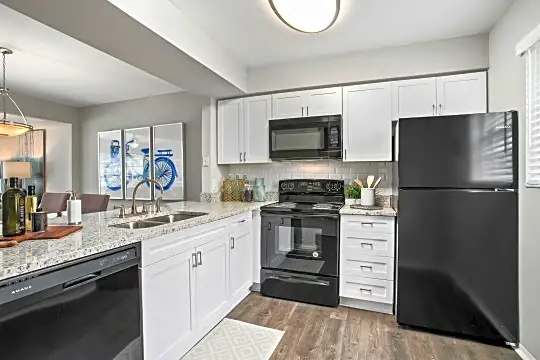 kitchen featuring refrigerator, electric range oven, microwave, stainless steel dishwasher, white cabinets, pendant lighting, light stone countertops, and light hardwood flooring