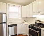 kitchen featuring range hood, stainless steel appliances, gas range oven, light granite-like countertops, white cabinets, and dark floors, 1026 Washington Apartments