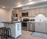 kitchen featuring a kitchen island, a breakfast bar, stainless steel appliances, electric range oven, light brown cabinets, and light hardwood floors, The Byway