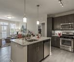 kitchen featuring a kitchen island, dishwasher, stainless steel microwave, refrigerator, gas range oven, light hardwood floors, dark brown cabinets, pendant lighting, and light stone countertops, The Vine