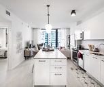 kitchen featuring a center island, natural light, electric range oven, microwave, stainless steel refrigerator, TV, light hardwood floors, white cabinetry, pendant lighting, and light stone countertops, Gio Midtown