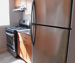 kitchen featuring natural light, stainless steel refrigerator, gas range oven, extractor fan, light floors, and brown cabinets, Creekside South Apartments