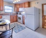 kitchen with natural light, gas range oven, refrigerator, dishwasher, microwave, dark countertops, light tile flooring, and brown cabinets, Homestead Apartments