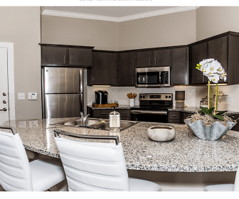 kitchen with electric range oven, stainless steel appliances, stone countertops, dark brown cabinetry, and dark floors, The Reserve on Bayou Desiard