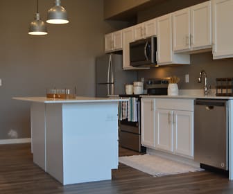 kitchen with a kitchen island, stainless steel appliances, range oven, white cabinetry, dark parquet floors, light countertops, and pendant lighting, 29 West Apartments