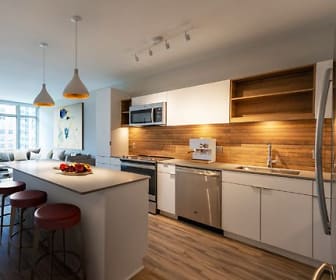 kitchen featuring stainless steel appliances, range oven, white cabinets, light countertops, pendant lighting, and light hardwood flooring, The Sur