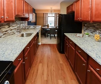 kitchen with natural light, refrigerator, dishwasher, light stone countertops, light hardwood floors, pendant lighting, and brown cabinets, Montgomery Manor Apartments & Townhomes