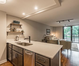kitchen featuring wood beam ceiling, natural light, stainless steel dishwasher, light hardwood floors, dark brown cabinetry, kitchen island sink, and light countertops, The Edge @ Sheridan