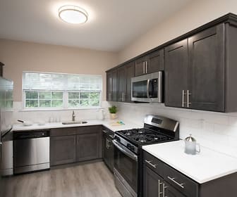 kitchen with natural light, gas range oven, stainless steel appliances, dark brown cabinetry, light countertops, and light parquet floors, Fair Lawn Commons