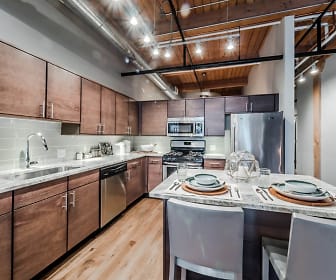 kitchen featuring beamed ceiling, stainless steel appliances, range oven, light stone countertops, brown cabinets, and light flooring, Lofts at River East