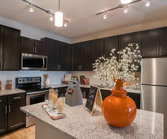 kitchen featuring a center island, stainless steel microwave, refrigerator, electric range oven, dark brown cabinetry, pendant lighting, light stone countertops, and light hardwood flooring, Palms at Magnolia Park