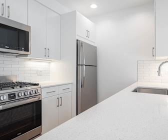 kitchen with gas range oven, stainless steel appliances, white cabinets, and light stone countertops, 600 Washington