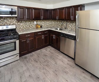 kitchen with stainless steel appliances, gas range oven, light parquet floors, light granite-like countertops, and dark brown cabinets, Henry On The Park Apartment Homes