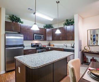 kitchen featuring a kitchen island, gas range oven, stainless steel appliances, dark brown cabinets, pendant lighting, light stone countertops, and light hardwood flooring, The Reserve at Riverdale