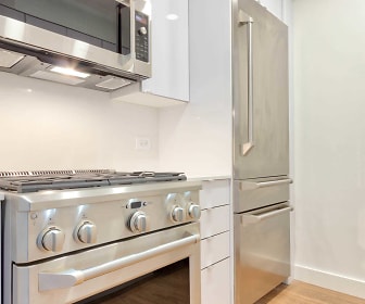 kitchen featuring refrigerator, gas range oven, stainless steel microwave, white cabinetry, and dark floors, 600 Washington