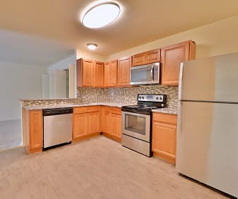kitchen featuring stainless steel appliances, electric range oven, light granite-like countertops, light hardwood floors, and brown cabinetry, St. Mary's Landing Apartments and Townhomes