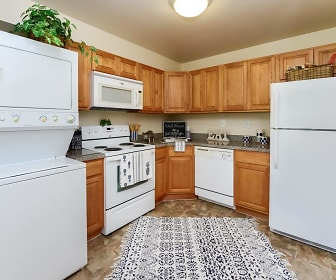 kitchen with refrigerator, microwave, electric range oven, washer / dryer, dishwasher, dark countertops, light tile floors, and brown cabinetry, Sherwood Village Apartment Homes