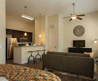 living room with a ceiling fan, a kitchen breakfast bar, stainless steel refrigerator, TV, and microwave, Ayrsley Lofts