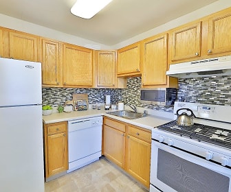 kitchen with refrigerator, ventilation hood, microwave, dishwasher, gas range oven, light tile flooring, brown cabinets, and light countertops, Gwynn Oaks Landing