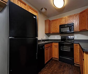 kitchen with refrigerator, microwave, dishwasher, range oven, dark countertops, brown cabinets, and dark hardwood flooring, Lion's Gate Townhomes
