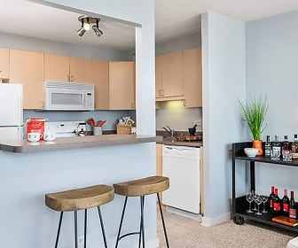 kitchen featuring a breakfast bar, refrigerator, dishwasher, range oven, microwave, light flooring, light countertops, and light brown cabinets, Park Michigan Apartments