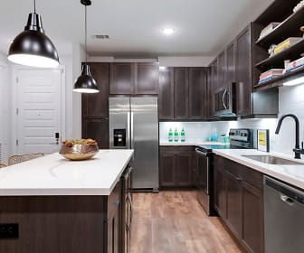 kitchen featuring a center island, electric range oven, stainless steel appliances, pendant lighting, light countertops, dark brown cabinets, and light hardwood flooring, Gables Water Street