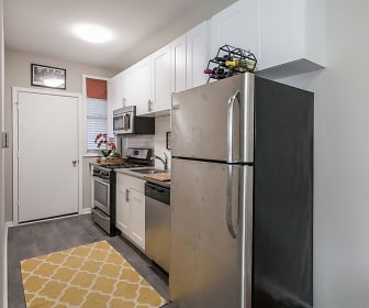 kitchen with stainless steel refrigerator, gas range oven, dishwasher, microwave, dark countertops, dark parquet floors, and white cabinets, The Maynard at Elaine Place