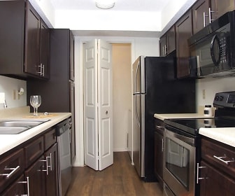 kitchen with refrigerator, electric range oven, dishwasher, microwave, dark brown cabinetry, light countertops, and dark hardwood flooring, Sherwood Apartments
