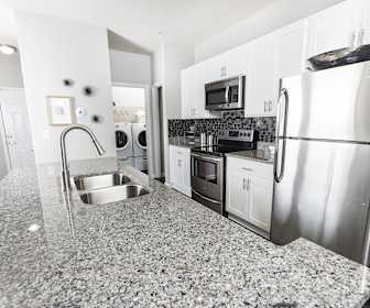 kitchen featuring washer / dryer, electric range oven, stainless steel appliances, stone countertops, and white cabinetry, Ansley At Town Center