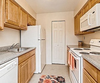 kitchen with electric range oven, refrigerator, dishwasher, microwave, light tile floors, stone countertops, and brown cabinetry, Lincoln Park Apartment Homes