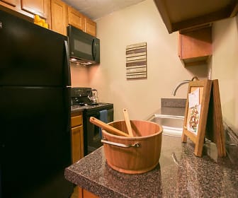 kitchen with carpet, range oven, refrigerator, microwave, dark countertops, and brown cabinets, Solon Club Apartments