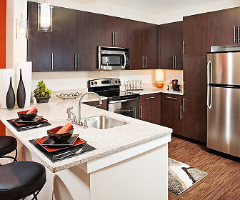 kitchen with a breakfast bar, electric range oven, stainless steel appliances, dark brown cabinetry, light countertops, pendant lighting, and dark hardwood floors, Palette at Arts District