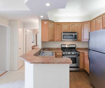 kitchen featuring gas range oven, stainless steel appliances, light flooring, light countertops, and brown cabinetry, Academy Village