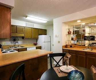 kitchen with a kitchen breakfast bar, refrigerator, dishwasher, pendant lighting, brown cabinets, and light countertops, Riverwind Apartment Homes