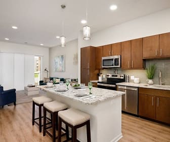 kitchen featuring a kitchen breakfast bar, stainless steel appliances, range oven, dark brown cabinets, light granite-like countertops, pendant lighting, and light parquet floors, The Residences at Park Place