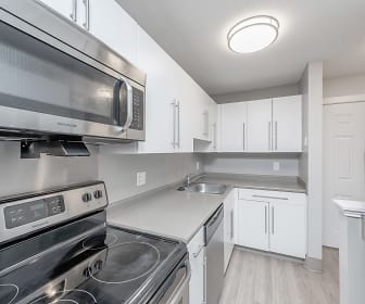 kitchen featuring stainless steel microwave, refrigerator, dishwasher, white cabinets, light countertops, and light parquet floors, Station Pointe