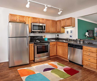 kitchen with electric range oven, stainless steel appliances, dark stone countertops, brown cabinets, and light parquet floors, Springfield Apartments