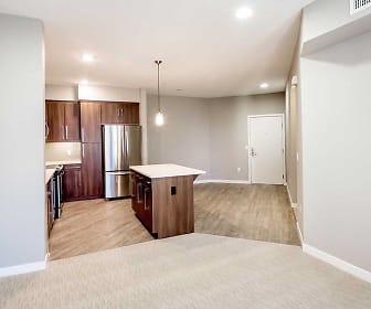 kitchen with carpet, a kitchen island, stainless steel refrigerator, light countertops, pendant lighting, light floors, and brown cabinets, Avalon Dublin Station