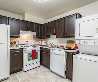 kitchen with ventilation hood, gas range oven, dishwasher, washer / dryer, refrigerator, dark brown cabinetry, light countertops, and light tile flooring, The Apartments at Bonnie Ridge