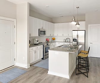 kitchen with a kitchen breakfast bar, stainless steel refrigerator, range oven, microwave, white cabinetry, light flooring, and pendant lighting, Ansley Park
