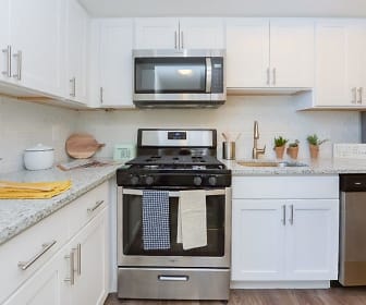 kitchen with stainless steel appliances, gas range oven, white cabinetry, dark floors, and light countertops, Strafford Station Apartment Homes