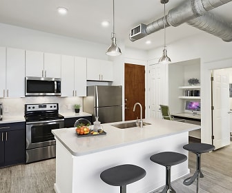 kitchen featuring a breakfast bar area, stainless steel appliances, electric range oven, white cabinetry, light countertops, kitchen island sink, light hardwood flooring, and pendant lighting, Camden City Centre