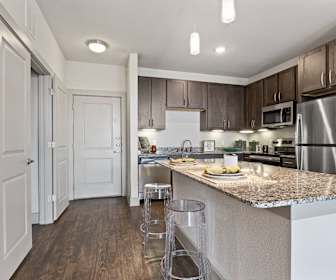 kitchen with a kitchen island, stainless steel appliances, range oven, dark hardwood floors, dark granite-like countertops, pendant lighting, and dark brown cabinetry, Oaks On Marketplace
