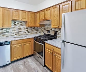 kitchen featuring refrigerator, stainless steel dishwasher, range hood, gas range oven, light parquet floors, light granite-like countertops, and brown cabinetry, Chesterfield Apartments