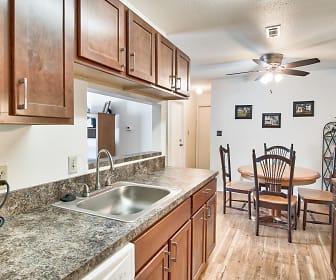 kitchen featuring a ceiling fan, range oven, dishwasher, dark granite-like countertops, light hardwood flooring, and brown cabinetry, Village Green