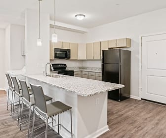 kitchen with a kitchen breakfast bar, refrigerator, range oven, microwave, light floors, light brown cabinetry, pendant lighting, and light stone countertops, Rivers Walk