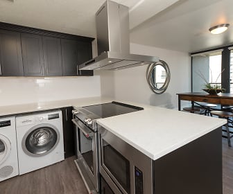 laundry room with parquet floors, a kitchen island, electric range oven, stainless steel finishes, independent washer and dryer, and exhaust hood, Harrison Tower Apartments