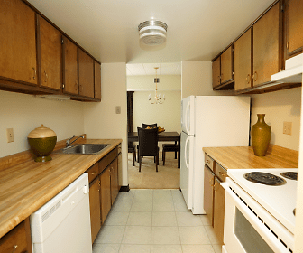 kitchen with refrigerator, electric range oven, dishwasher, fume extractor, pendant lighting, light countertops, light tile floors, and brown cabinetry, Toftrees Apartments