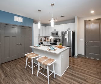 kitchen with a breakfast bar area, stainless steel refrigerator, microwave, range oven, dark parquet floors, pendant lighting, white cabinets, and light granite-like countertops, Olympus Emerald Coast